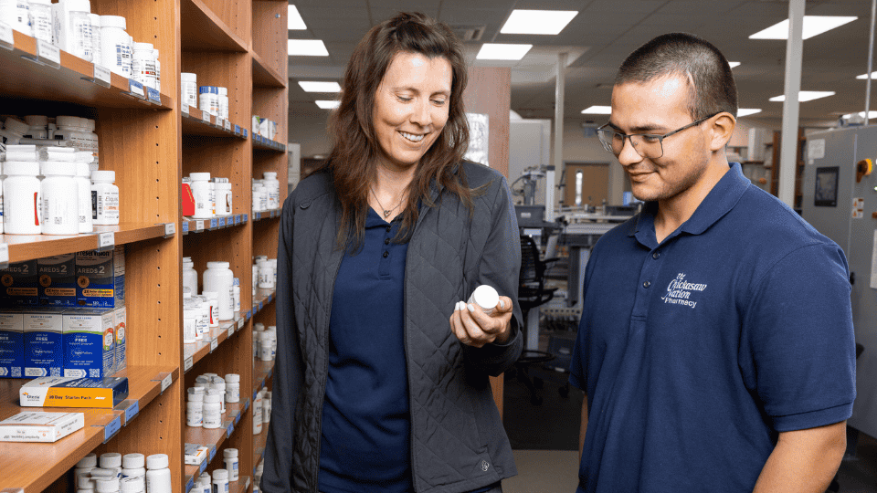 A Chickasaw Nation pharmacy resident receives hands-on guidance from a preceptor while reviewing medication in the pharmacy.