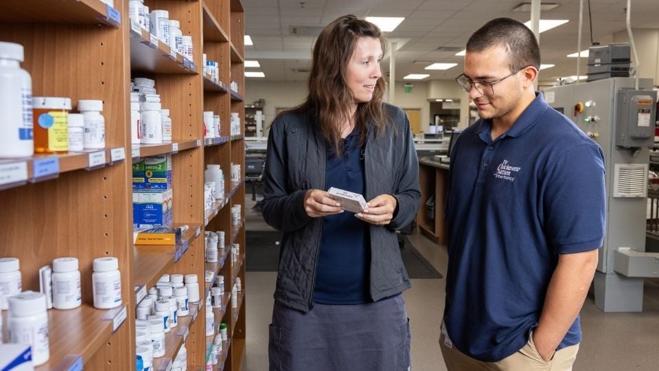 Pharmacist mentoring a pharmacy resident in the Chickasaw Nation Department of Health pharmacy, emphasizing hands-on training and collaborative learning within the residency program.